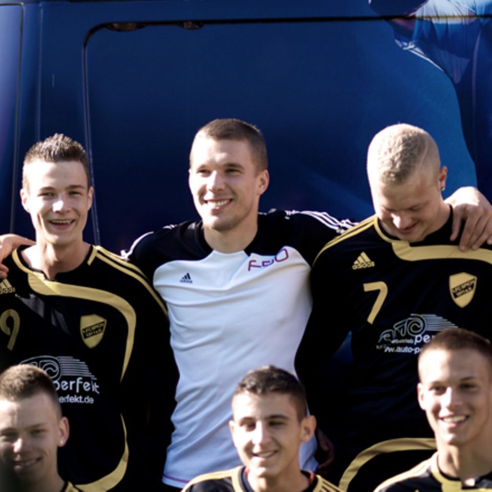 Lukas Podolski unverkleidet beim Überraschungsbesuch einer Jugend-Fußballmannschaft im Rahmen eines Werbedrehs.