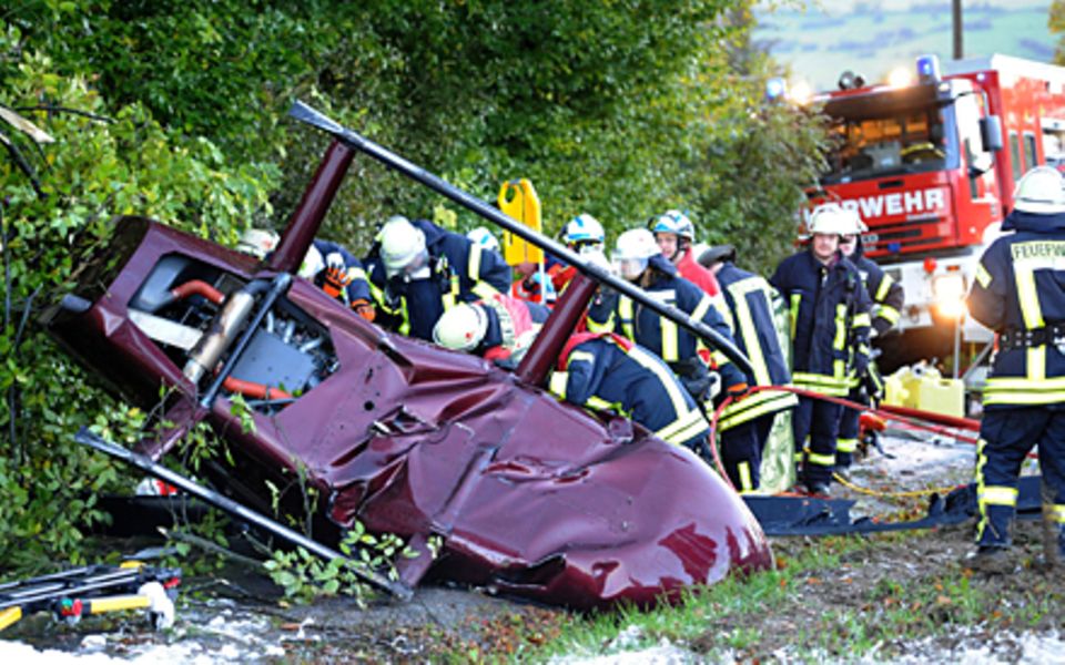 Rettungssanitäter und Feuerwehr leisten am Wrack des verunglückten Hubschraubers erste Hilfe.