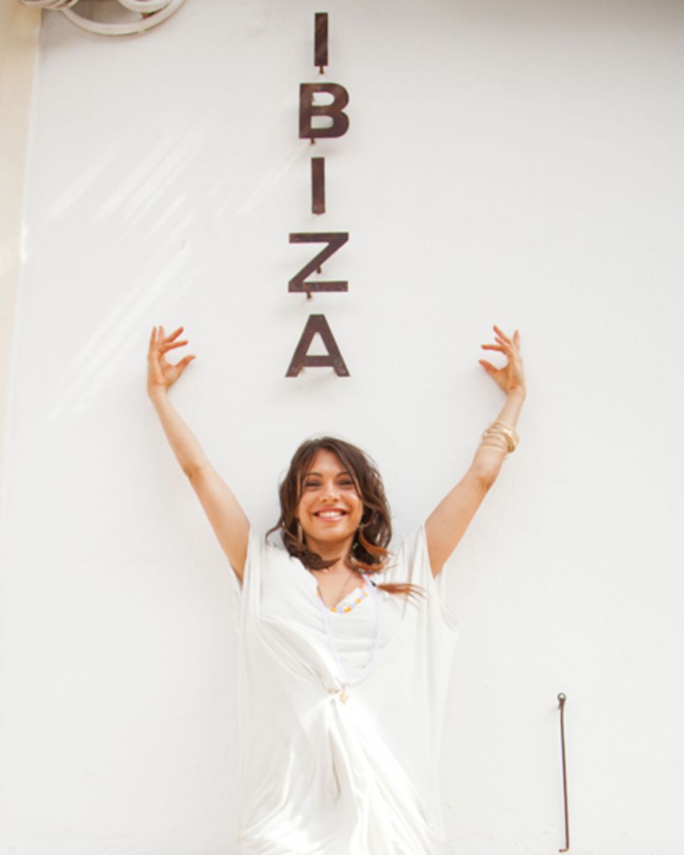 Urlaubsfeeling: Jana in vor einem "Ibiza" Schriftzug an einer Hauswand.