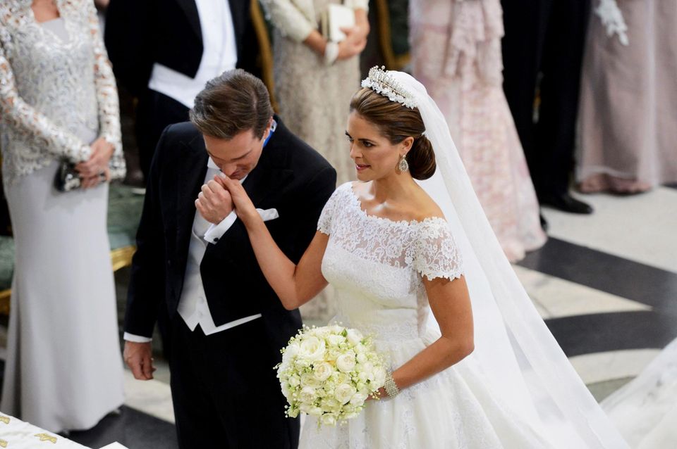 Ein ergriffener Bräutigam küsst die Hand seiner Braut, die sich insgesamt sehr königlich zeigt.