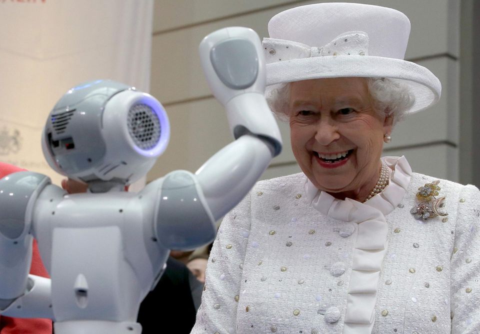 Dass der Roboter ihr auf Kommando zuwinkt, amüsiert die Queen offenbar.