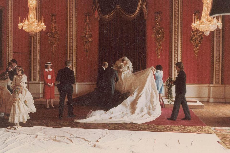 Prinzessin Diana: Prinzessin Dianas Brautkleid von der Designerin Elizabeth Emanuel wird für ein offizielles Hochzeitsfoto drapiert. Dafür musste die acht Meter lange Schleppe aus englische Seide in Position gebracht werden Prinzessin Dianas Brautkleid von der Designerin Elizabeth Emanuel wird für ein offizielles Hochzeitsfoto drapiert. Dafür musste die acht Meter lange Schleppe aus englische Seide in Position gebracht werden