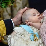 Liebevoll streicht König Carl Gustaf seiner jüngsten Enkelin, die weiter friedlich schlummert, über den Kopf.