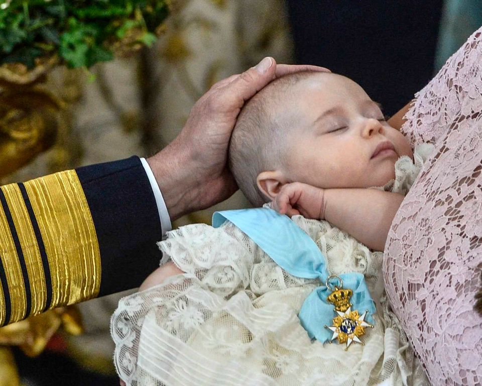 Prinzen-Taufe in Schweden: Prinzessin Leonore mit dem Seraphinen-Orden bei ihrer Taufe 2014. Liebevoll streicht König Carl Gustaf seiner jüngsten Enkelin, die weiter friedlich schlummert, über den Kopf.