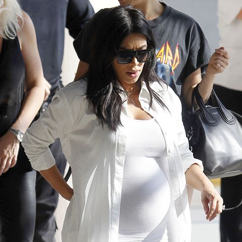 Kim Kardashians Babybauch wächst rasant. Das kann man im engen, weißen Schlauchkleid, über dem sie ein passendes langes Hemd trägt besonders gut sehen.