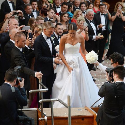 Umrahmt von 300 Gästen hilft Bastian Schweinsteiger seiner schönen Braut ins Wassertaxi, mit dem die Frischverheirateten nach der Trauung zur Hochzeitsparty gebracht werden.