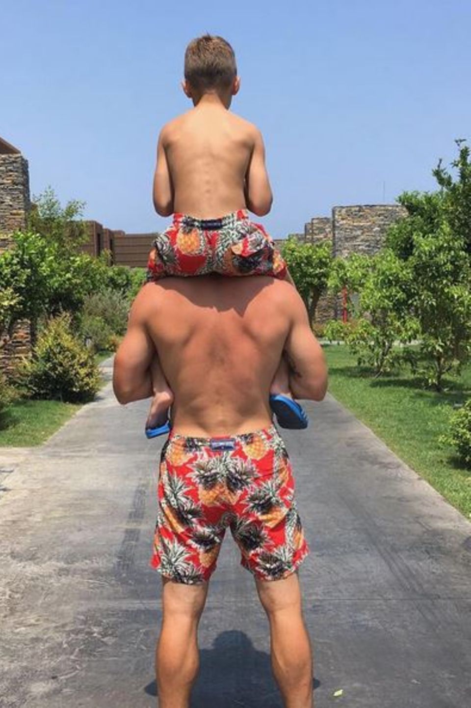 Lukas Podolski trägt Sohn Lois auf den Schultern: Sehr trendig sind auch die Ananas-Badehosen im Partnerlook. Lukas Podolski trägt Sohn Lois auf den Schultern: Sehr trendig sind auch die Ananas-Badehosen im Partnerlook.