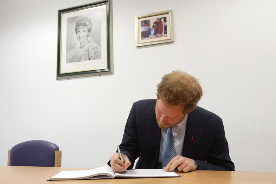 Prinz Harry: Bei seinem (offiziellen) Besuch im Dezember 2015 trägt sich Prinz Harry in Mildmay ins Gästebuch ein. An der Wand erinnern Bilder an seine verstorbene Mutter Diana. Bei seinem (offiziellen) Besuch im Dezember 2015 trägt sich Prinz Harry in Mildmay ins Gästebuch ein. An der Wand erinnern Bilder an seine verstorbene Mutter Diana.