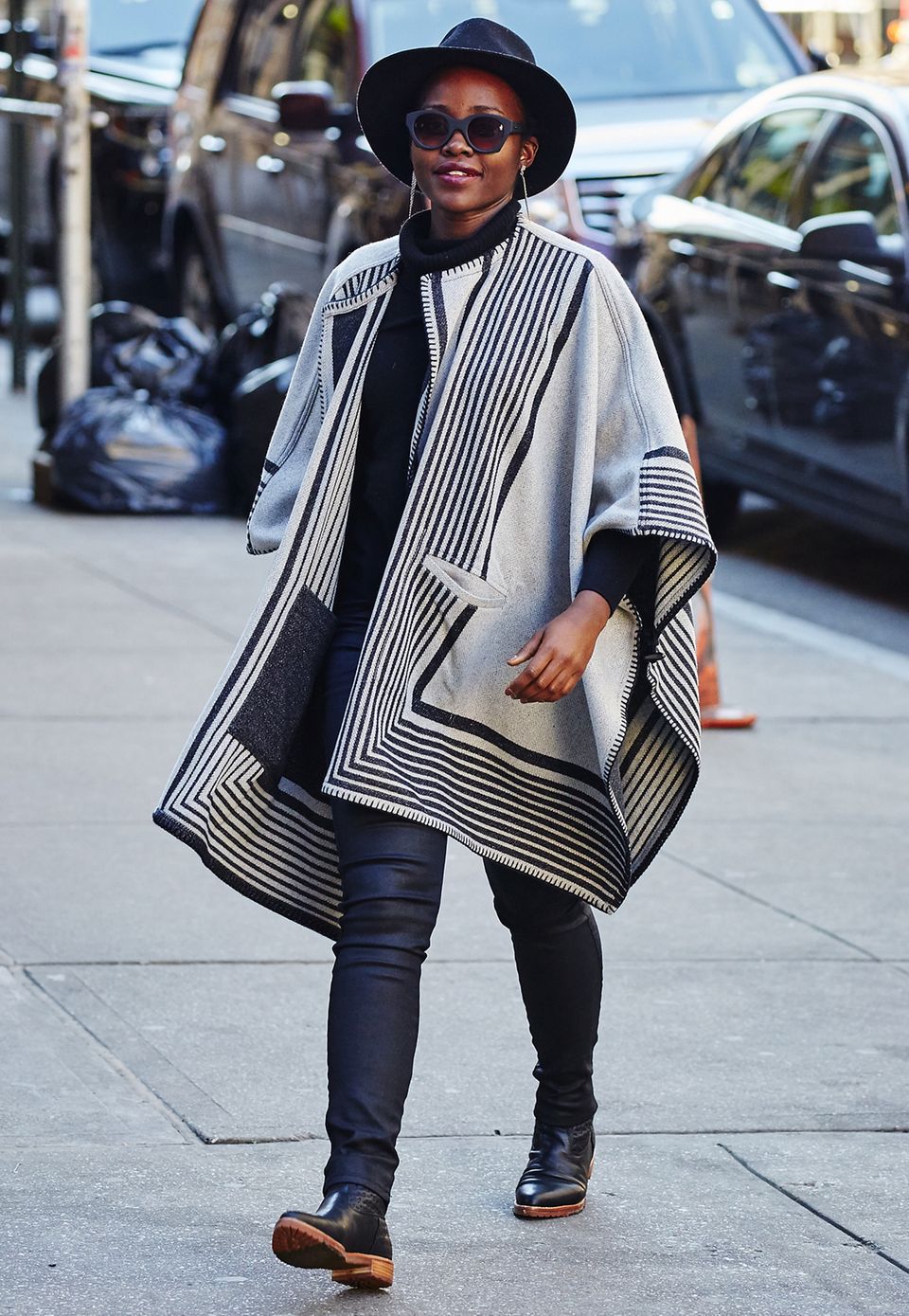 Lupita Nyong'o hüllt sich zum Schutz gegen die Kälte in ein schwarz-weißes Cape im Ethno-Style und trägt damit das Trendteil der diesjährigen Herbst/Winter-Saison.