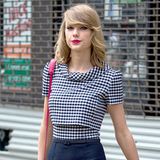 Das sehr klassische Karo-Muster ihres Etuikleides peppt Taylor Swift mit einer himbeerroten Schultertasche und türkisen Fingernägeln auf.