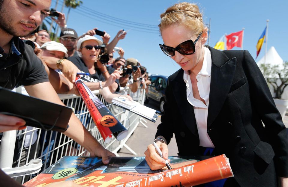 Bei den Filmfestspielen in Cannes verteilt Uma Thurman Autogramme an ihre Fans. Einer hat extra sein "Pulp Fiction"-Filmplakat zum Signieren mitgebracht.