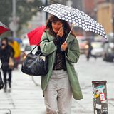 Helena Christensen läuft telefonierend und mit Pünktchenschirm durch das regnerische New York.