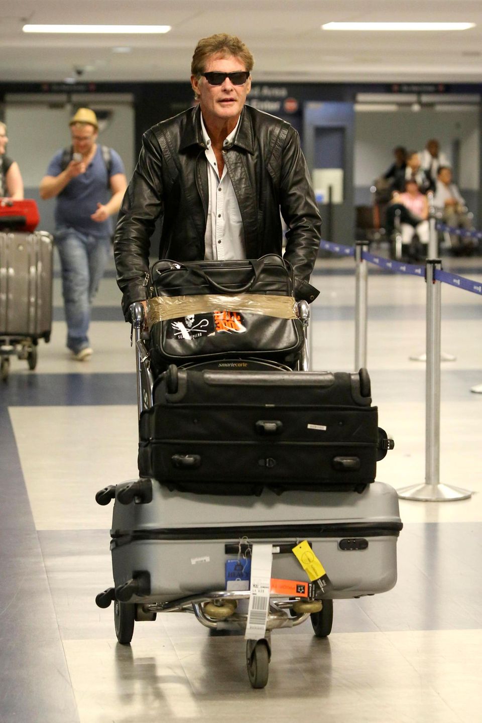 Nach seinem Flug von Berlin nach Los Angeles schiebt David Hasselhoff sein Gepäck über den Flughafen. Nach seinem Flug von Berlin nach Los Angeles schiebt David Hasselhoff sein Gepäck über den Flughafen.