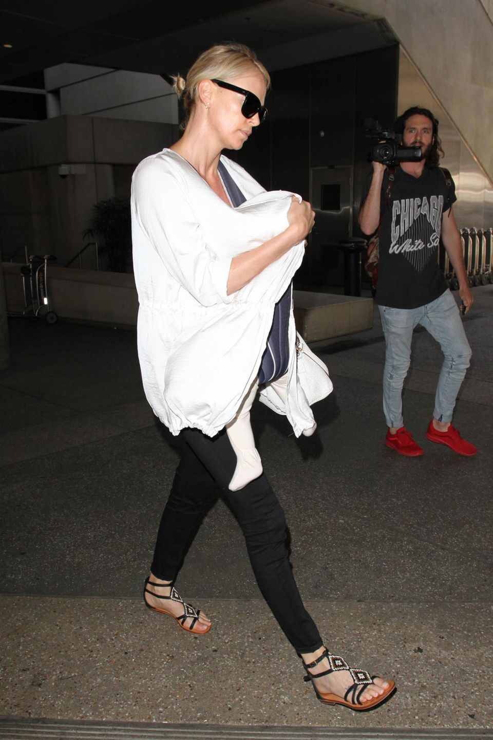 Charlize Theron schützt sich am Flughafen von Los Angeles vor dem Blitzlicht der Paparazzi mit einer großen Sonnenbrille. Auch gut versteckt: Ihre Tochter August.