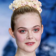 "Maleficent"-Star Elle Fanning präsentiert nicht nur ein avantgardistisches Augen-Make-up, sondern unterstreicht ihren elfengleichen Look auch mit zartgelben Kunstblumen in ihrer Hochsteckfrisur.