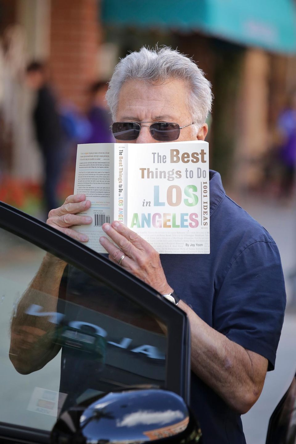 Nach seinem Arztbesuch versteckt sich Dustin Hoffman vor den Paparazzis hinter seinem Buch "The Best Things To Do In Los Angeles - 1001 Ideas".
