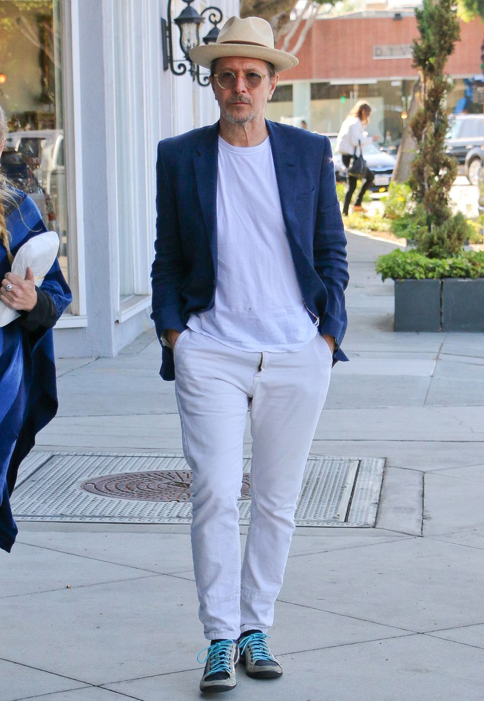 Sommerlich-maritim mit weißen Jeans, T-Shirt, blauem Sakko und Bast-Fedora zieht Gary Oldman durch die Nachbarschaft von West Hollywood.
