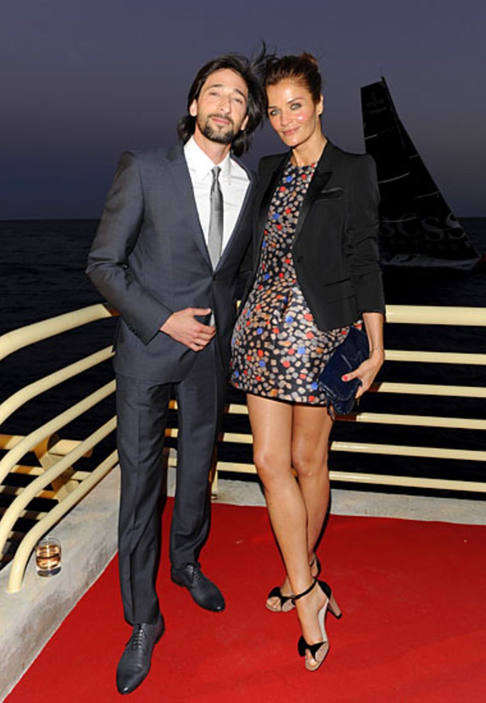 Adrien Brody und Helena Christensen, beide in BOSS Black, lassen sich auf der Terrasse der Villa Key Largo den abendlichen Somme
