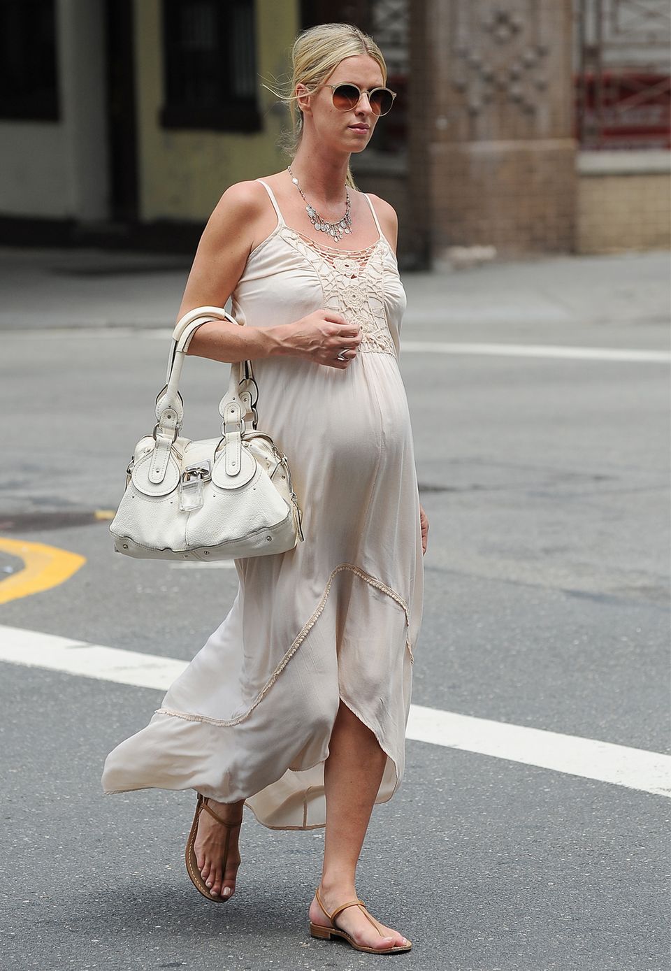 Nicky Hilton beweist wieder einmal Stilgefühl und macht auch in weiten Kleidern eine gute Figur. Das mit Spitze besezte Naturweiße Kleid hat sie mit einer weißen Handtasche kombiniert. Immer dabei: Ihre braunen Riemchen-Sandalen.