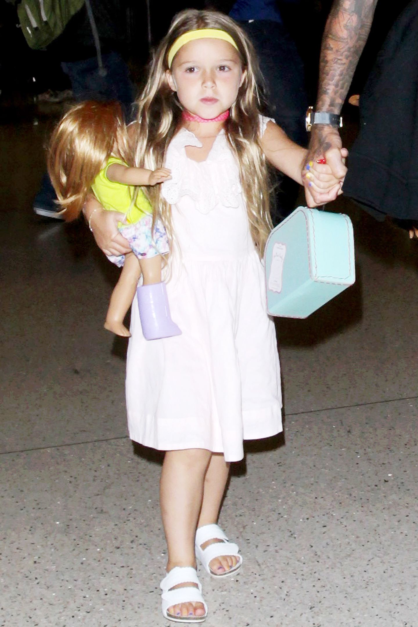 Die Nägel bunt lackiert, ein gelbes Stirnband und eine pinke Kette - So stylish geht Beckham-Töchterchen Harper mit ihrer Familie auf Reisen.