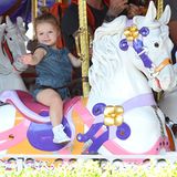 In einem gemütlichen Denim-Jumpsuit dreht Harper glücklich ihre Runden auf dem Karussel in Disneyland und winkt verträumt.