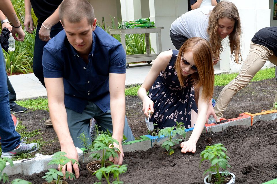 Die Schauspieler Andrew Garfield und Emma Stone bepflanzen in der "Hialeah Gardens Elementary School" in Florida mit Schülern ein Beet.