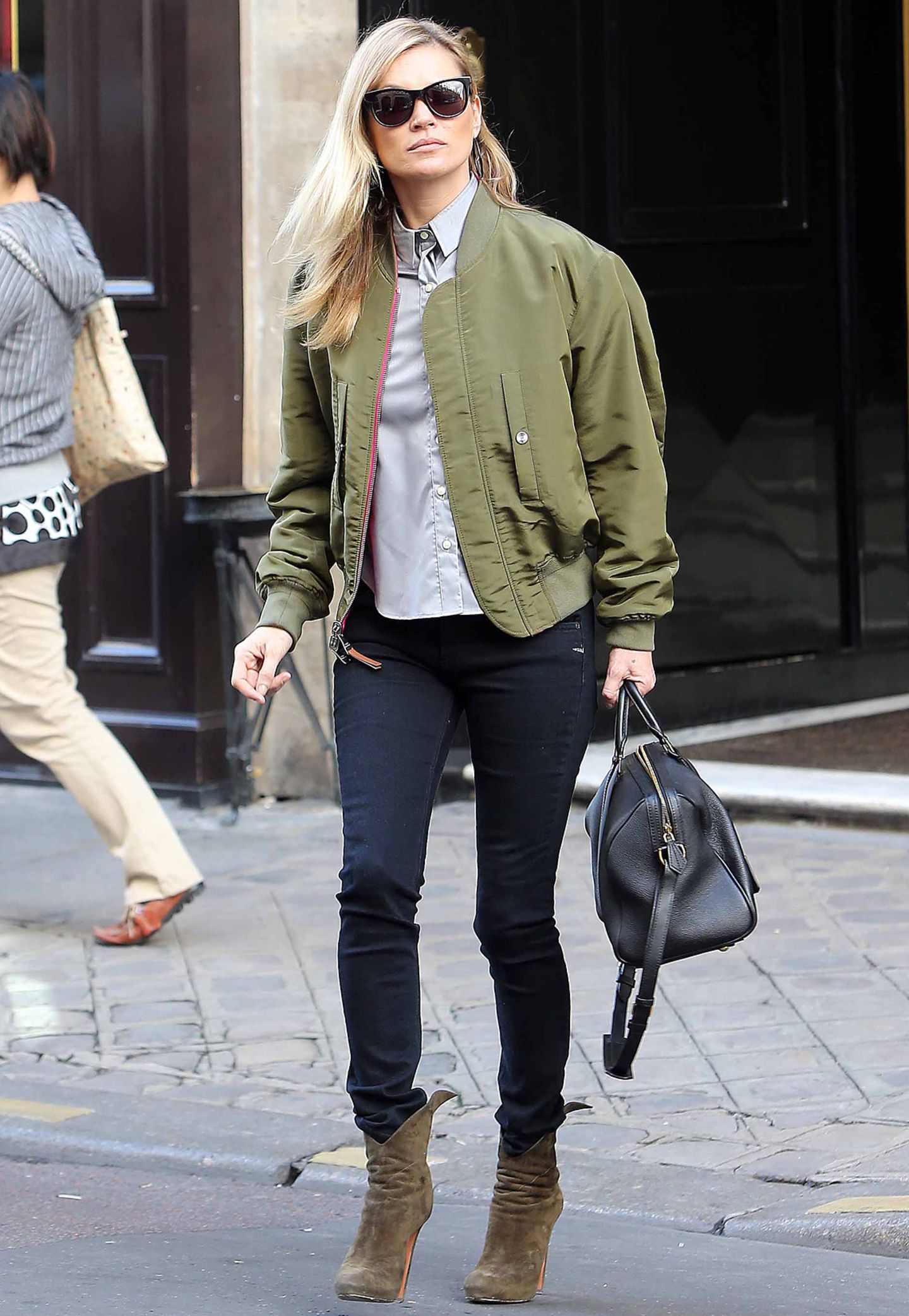 Im lässigen Preppy-Look schlendert Kate Moss durch die Straßen von Paris. Trotz gefährlichem Kopfsteinpflaster trägt das Supermodel extrem hohe Stiefeletten, um ihrem Outfit einen weiblichen Touch zu verpassen.