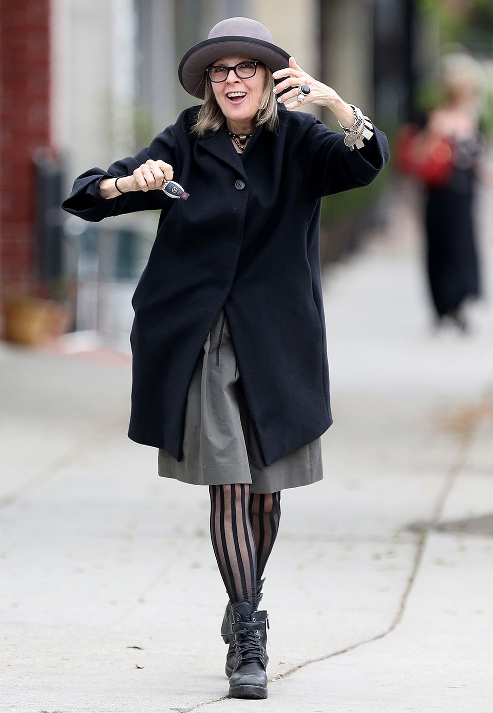 Hollywoodstar Diane Keaton kombiniert ihren schwarzen Eggshape-Mantel mit einem grauen Hut, gestreifter Strumpfhose und derben Schnürstiefeln.
