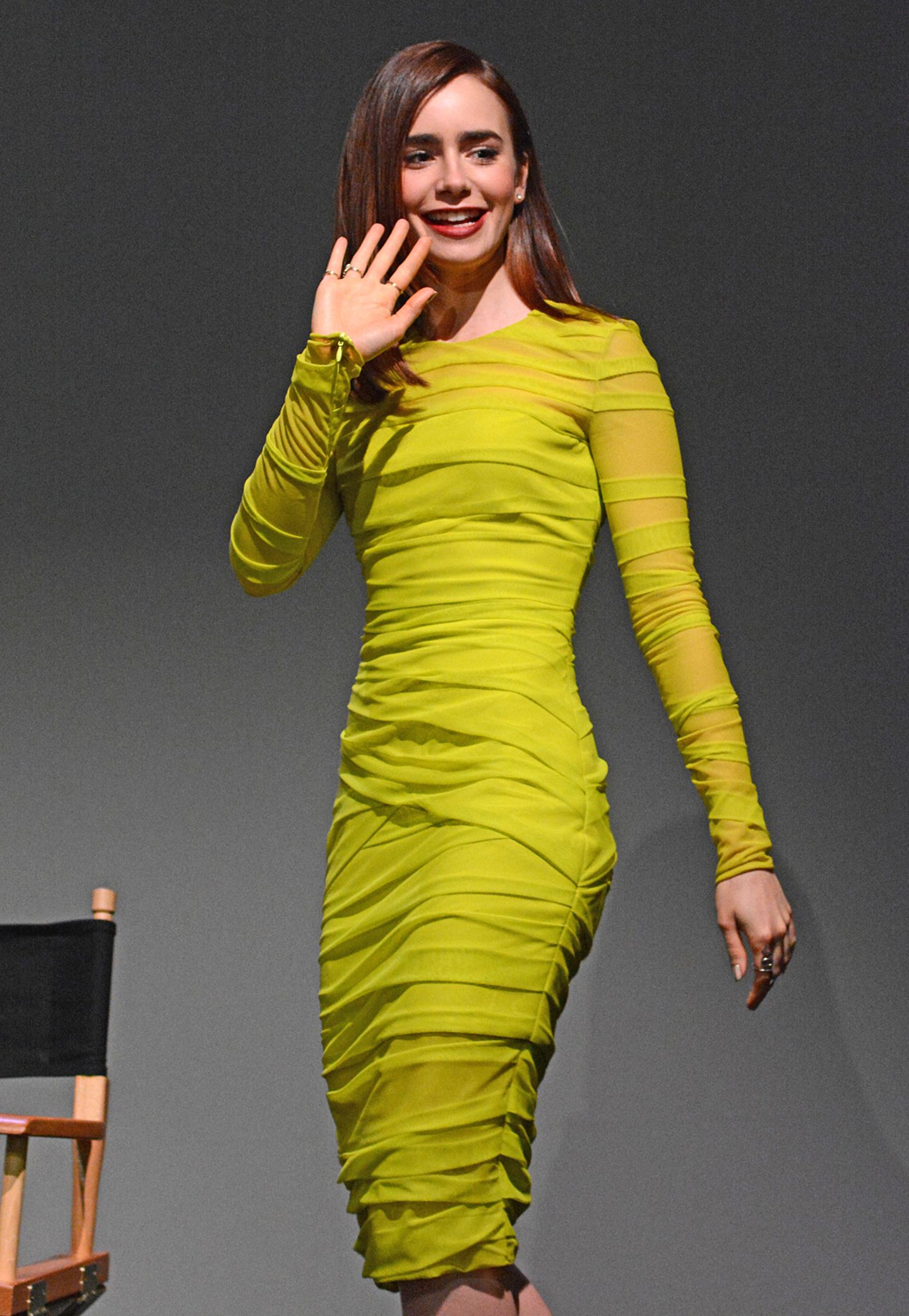 In einem neongelben Kleid von Versace leuchtet Lily Collins sogar auf einer dunklen Bühne.