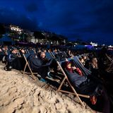 Dick eingepackt mummeln sich Festival-Zuschauer am Strand in ihre Liegestühle.