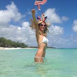 Heidi Klum schwenkt im weißen Bikini die amerikanische Flagge.