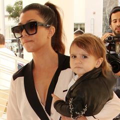 Mini-Fashionista Penelope lässt sich von Mama Kourtney Kardashian in cooler Lederjacke mit Ketten-Details tragen.
