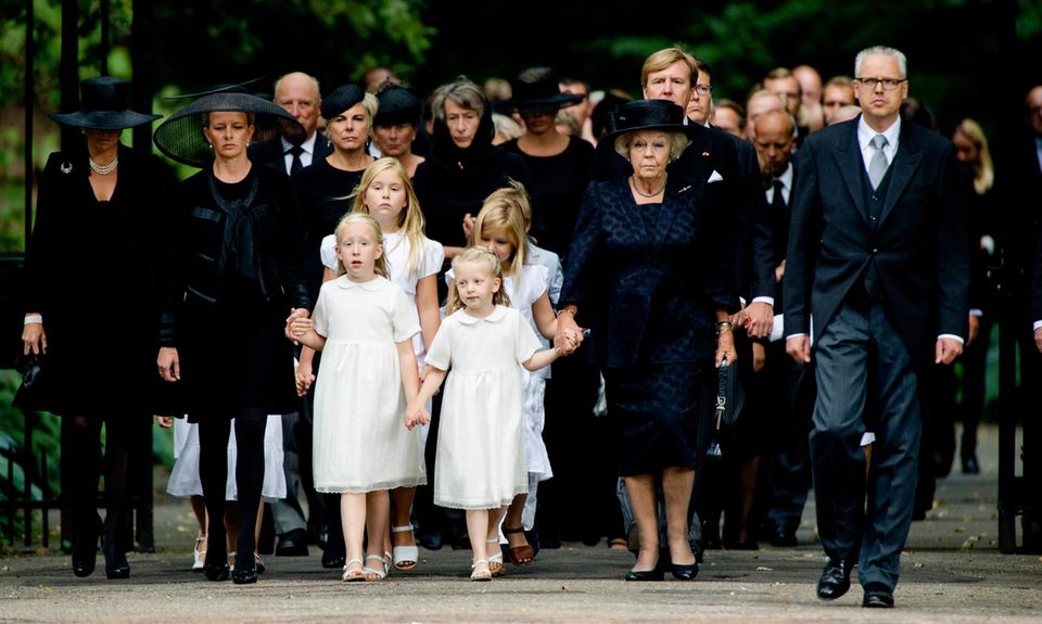 Geschlossen und sich an den Händen haltend betritt die niederländische Königsfamilie den Friedhof.