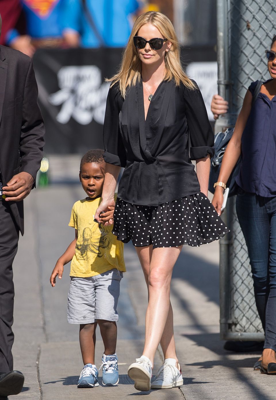Schick und sportlich: Charlize Theron besucht im kurzen Seiden-Kimono, Pünktchen-Rock und weißen Sneakern mit ihrem Sohn Jackson die TV-Show von Jimmy Kimmel.