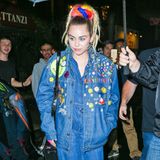 Mit der überweiten, mit Stickern übersäten Jeansjacke über dem Denim-Jumpsuit könnte Miley Cyrus geradewegs aus den Achtziger kommen. Und mitdem Dreadlock-Haarteil setzt sie sich selbst noch ganz persönlich die haarige Grusel-Krone auf.
