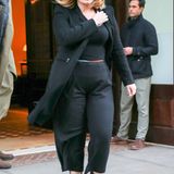 Schwarze Culottes, Stilettos mit Schnürung, taillierter, schwarzer Mantel, Sonnenbrille und Hut - Adele sieht aus wie ein echter Megastar.