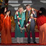 Tag 1  Charles und Camilla werden mit rot-weißen Blumenkränzen in Indien empfangen.