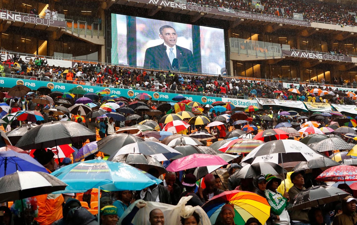 Bei Regenwetter kommen tausende Trauernde zum Stadion nach Johannesburg um an den Feierlichkeiten teilzunehmen.