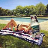Hilaria genießt den sommerlichen Sonntag am Pool und liest ganz entspannt in Fischpose die Zeitung.