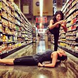 So ist Einkaufen ein Erlebnis: Hilaria Baldwin spritzt ihrer Freundin Senf aus der Tube, natürlich in komplizierter Yogastellung auf einem Bein.