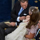 Chris O'Neill streichelt zärtlich seine Tochter, die von Mutter Madeleine während des Gottesdienstes immer wieder sanft geschaukelt wird. Das Taufkleid von Leonore wurde 1906 zum ersten Mal getregen, von Prinz Gustaf Adolf. Auch Prinzessin Victoria, Prinz Carl Philip, Prinzessin Madeleine und zuletzt Prinzessin Estelle trugen dieses Modell aus cremefarbenem Seidensatin.