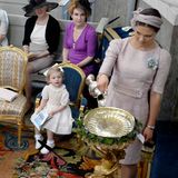 Prinzessin Victoria, als eine der Patinnen, gießt das Taufwasser ins Taufbecken. Es stammt aus einer Quelle in Öland, wo die Königsfamilie ihre Sommerresidenz hat. Prinzessin Estelle schaut ihrer Mutter dabei fasziniert zu.  Victoria trägt ein Kleid aus dem Hause "Dolce&Gabana".