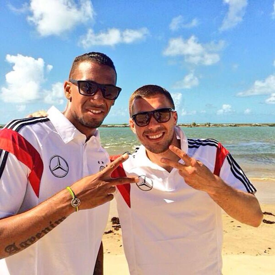 Jérôme Boateng und Lukas Podolski lassen sich am Strand die Sonne auf den Kopf scheinen.