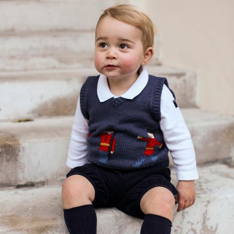 Prinz George trägt auf seinen Weihnachtsfotos eine kurze, schwarze Hose und dazu einen blauen Pullunder. Darauf zu erkennen sind, wie es sich für einen englichen Prinzen gehört, Gardisten mit Bärenfellmützen.