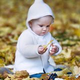 Zipfelmützchen und Strickcardigan sind für Estelle genau das Richtige zum Spielen im Herbstlaub.