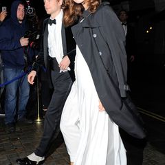 Eine gut gelaunte Keira Knightley bedeckt ihr weißes Kleid mit einem schwarzen Burberry-Trenchcoat.