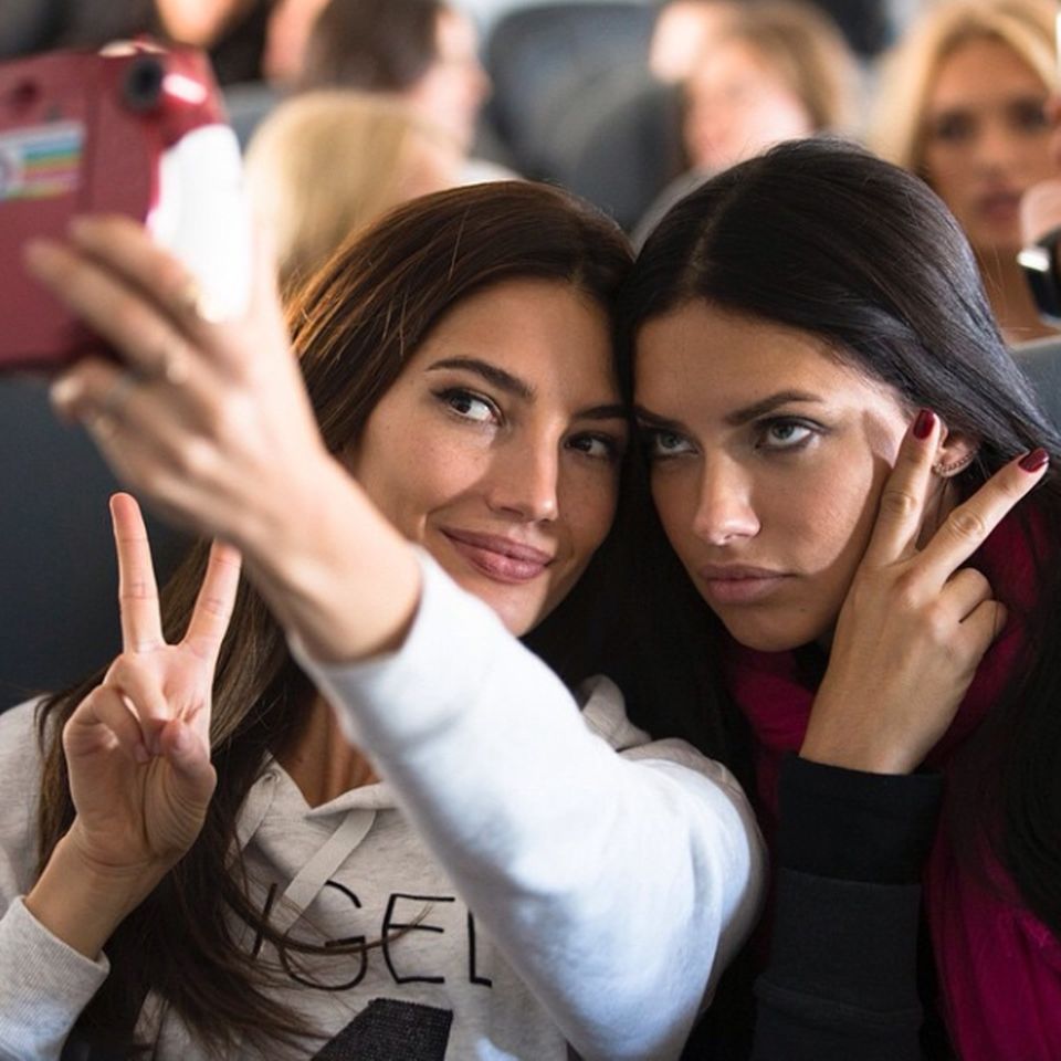 Im Flieger von New York nach London saßen Lily Aldridge und Adriana Lima nebeneinander und vertrieben sich ihre Zeit mit einer witzigen Selfie-Session.