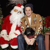 John Mayer ist in Weihnachtsstimmung! Er sitz bei einem schrägen Weihnachtsmann mit Hundegesicht und seinem täglichen Begleiter Moose in einem kuscheligen Cardigan.