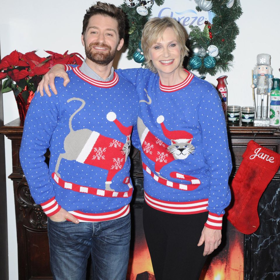 In weihnachtlichen Katzenpullovern posieren Matthew Morrison und Jane Lynch vor den Kameras.