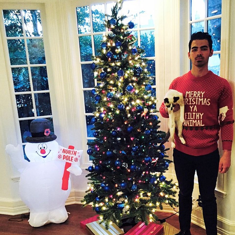 Joe Jonas scheint ein ganz besonderer Weihnachtsfan zu sein: Er wünscht mit seinem Pulli fröhliche Weihnachten und schickt gleich noch eine augenzwinkernde Beleidigung mit.
